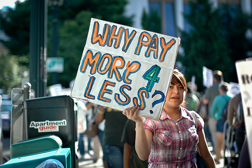 a protest sign says why pay more 4 less?