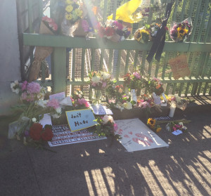 Memorial of flowers and a "don't hate" sign for Rick Best and Taliesin Meche