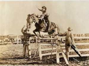 Image of rodeo cowgirl jumping her horse over a fence 