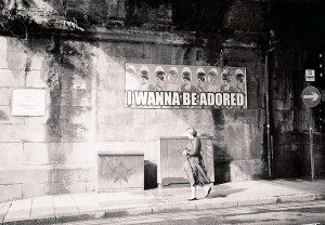 A picture of a street with the Stone Roses' "I Wanna Be Adored" poster on a wall, & the Self Help Radio logo added next to it.