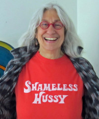 Judith Arcana in a t-shirt that says "Shameless Hussy"